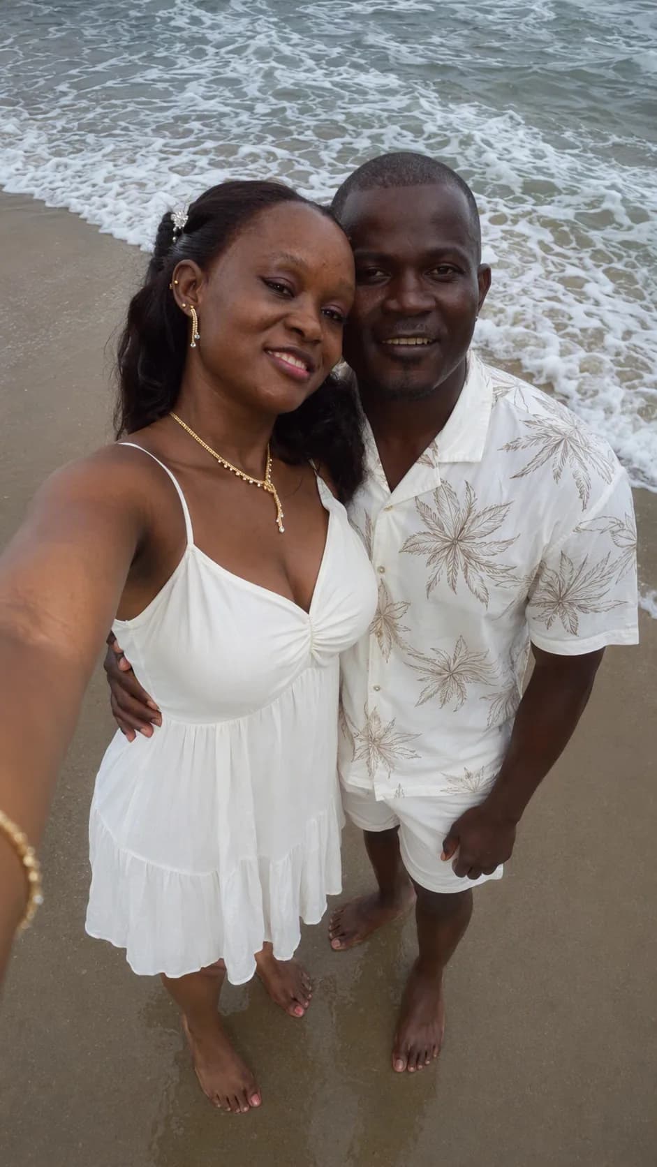 Richelle et Lionel serrés l'un contre l'autre au bord de l'eau, l'écume des vagues derrière eux.